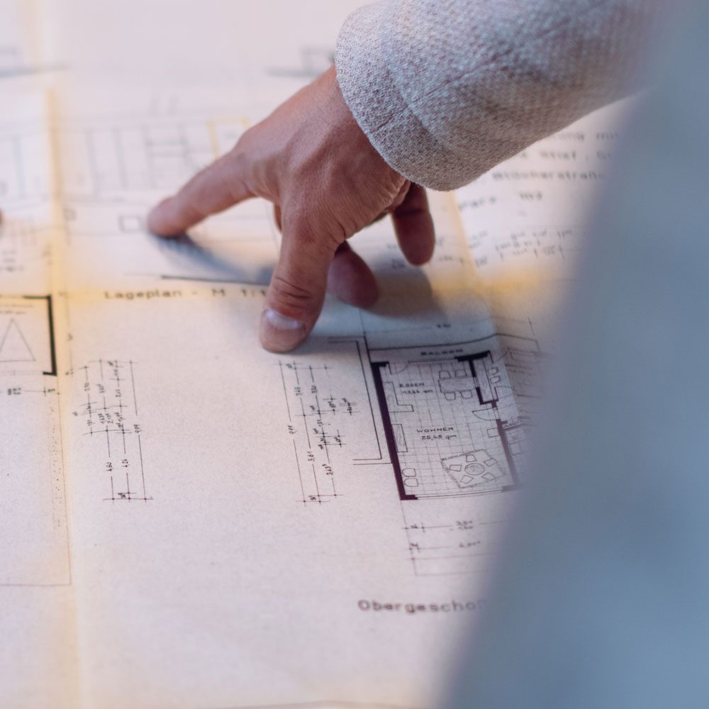 Hand zeigt auf Grundriss bei der Bewertung einer Immobilie