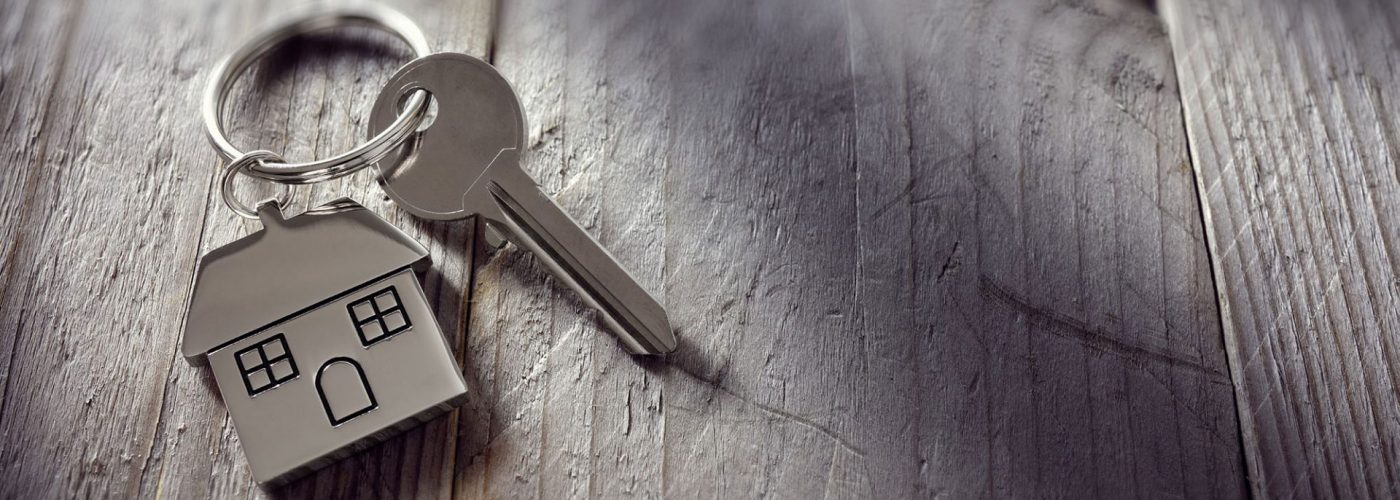 Hausschlüssel mit Hausanhänger als Symbol für Vermietung und Wohnen