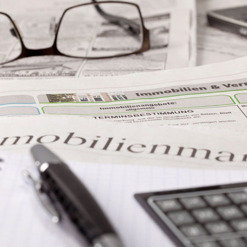 Zeitung mit Immobilienanzeigen, Taschenrechner und Notizbuch